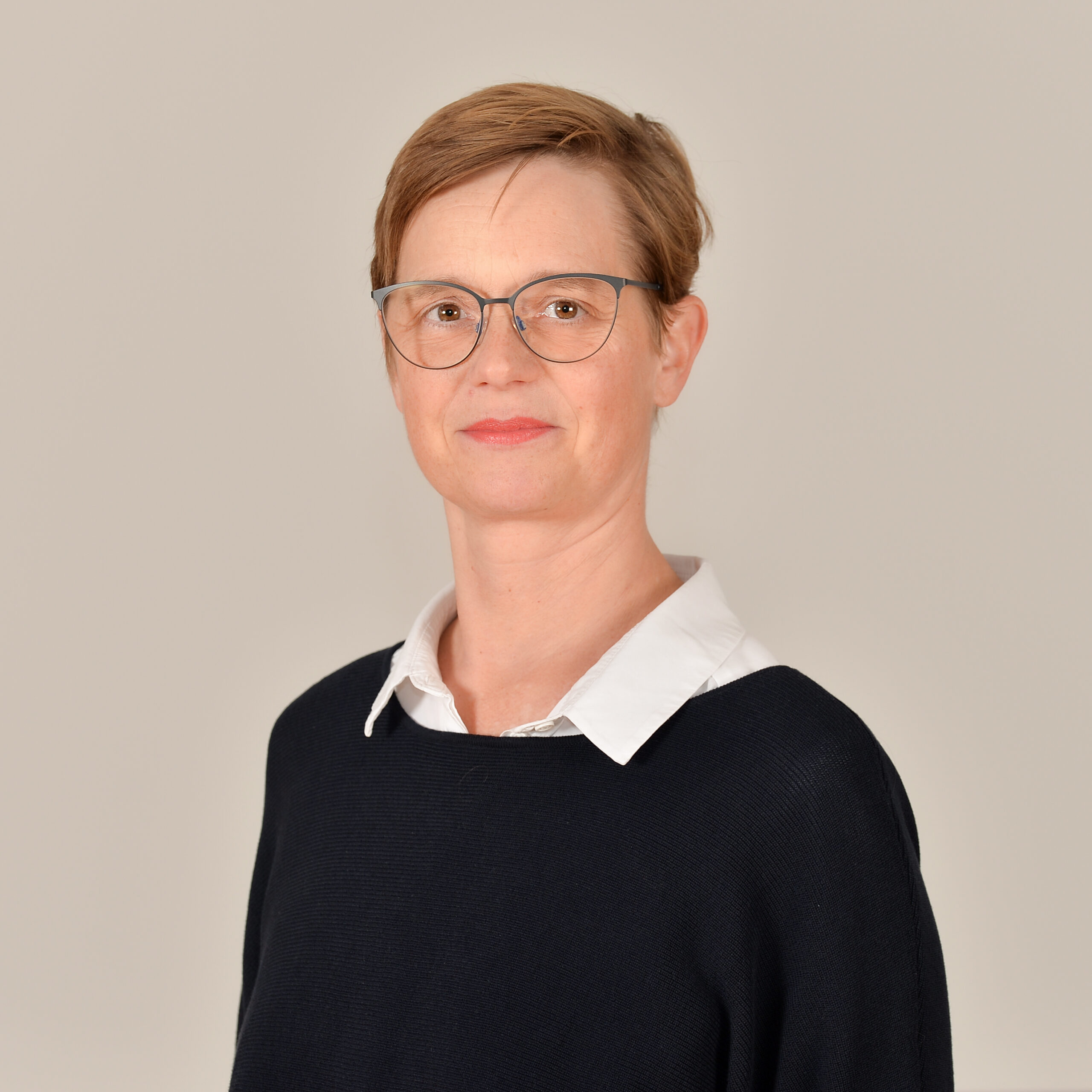 Profilbild von Dr. Marnie Schlüter in weißer Bluse und schwarzem Pullover.