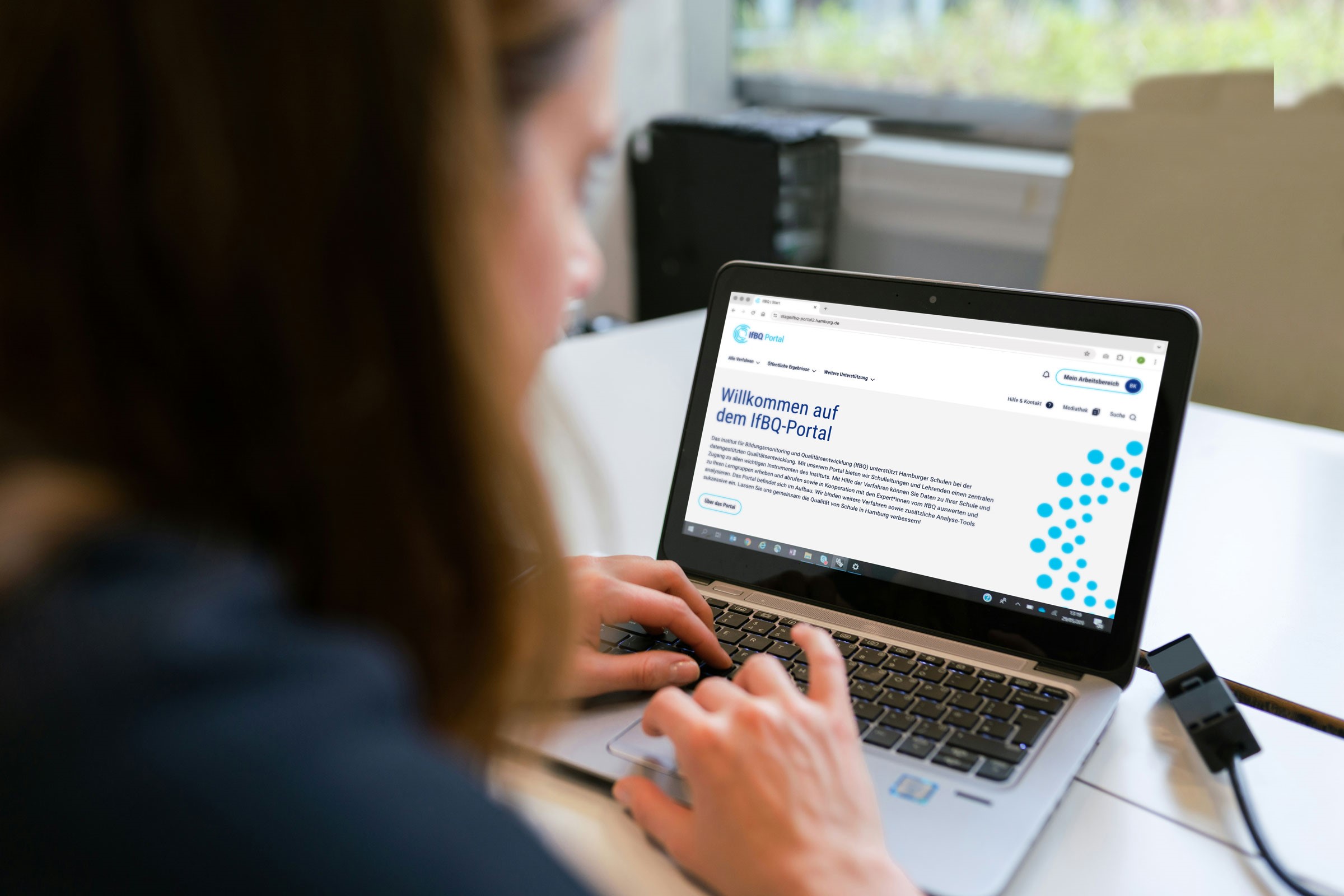 Eine Frau sitzt vor einem Laptop, auf dem die Startseite des IfBQ-Portals geöffnet ist.
